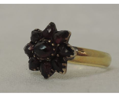 A lady's dress ring formed out of a yellow metal wedding band stamped 585 having an attached oval garnet daisy cluster, size 