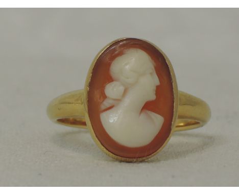 A lady's dress ring having a small cameo plaque in a collared mount on a yellow metal loop stamped 18ct,  size J/K