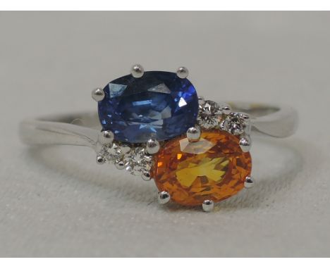 A lady's dress ring having two yellow and blue oval sapphires in a crossover setting with diamond chip decoration on an 18ct 