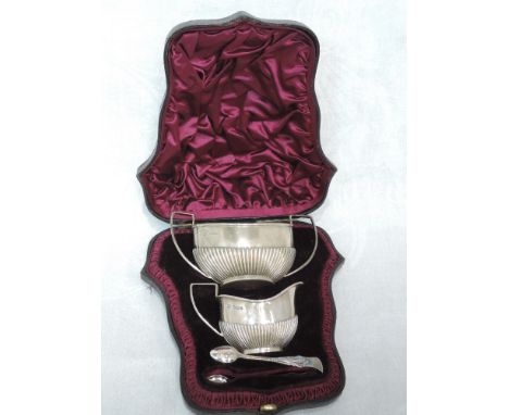 A cased Victorian silver three piece sugar and cream set having architectural handles and gadrooned decoration, Sheffield 189