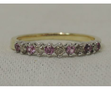 A half eternity ring having five diamond chips interspersed by six pink sapphire style stones in a claw set mount on a 9ct go