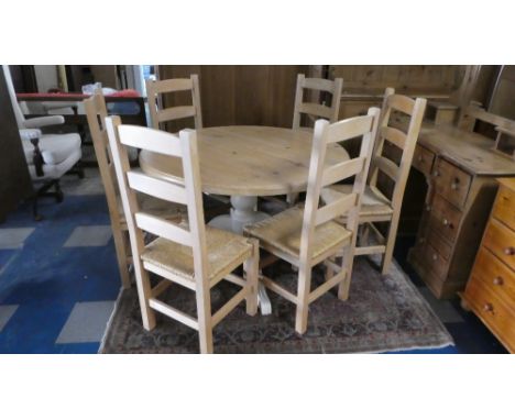 A Circular Pine Kitchen Table with Painted Tripod Base together with Six Rush Seated Ladder Back Chairs