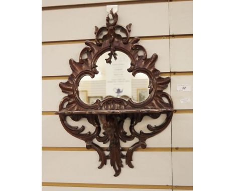 Possibly Victorian mirror with shaped glass plate in carved mahogany scrolling frame, with integral shelf, 42cm x 31cm approx