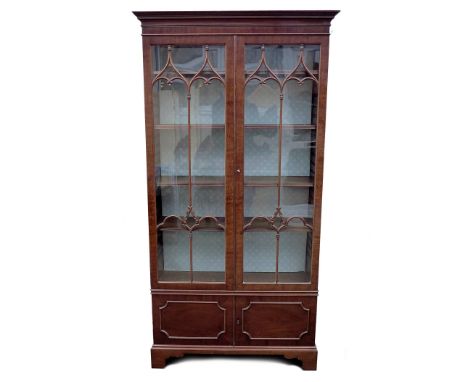 A mahogany bookcase, mid 20th century, with twin arched astragal glazed doors opening to reveal to five shelves, twin cupboar