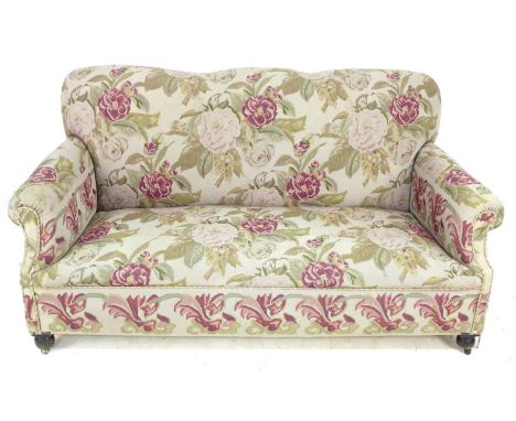 An Edwardian three seater sofa, upholstered in embroidered fabric patterned with large roses, turned feet and brass castors, 