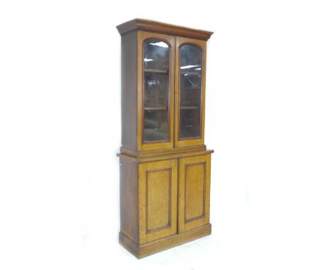 A narrow late Victorian mahogany glazed bookcase, with two glazed doors enclosing two shelves, the base section with cupboard