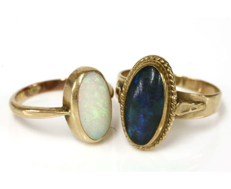 A gold single stone opal cabochon ring, rub set to a plain polished shank, 2.48g, and a gold single stone black opal doublet 