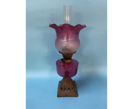 An oil lamp, with cranberry shade and reservoir