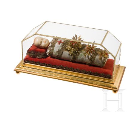   Fatschenkindl mit Wachskopf, in Vitrine, süddeutsch, 19. Jhdt.  Vollplastisch gearbeitet. Fein gewickeltes Christuskind mit