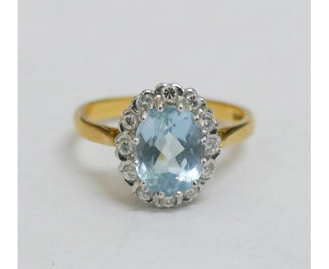 An 18 carat gold diamond and aquamarine oval cluster ring, the oval mixed cut aquamarine in claw setting within 12 round bril