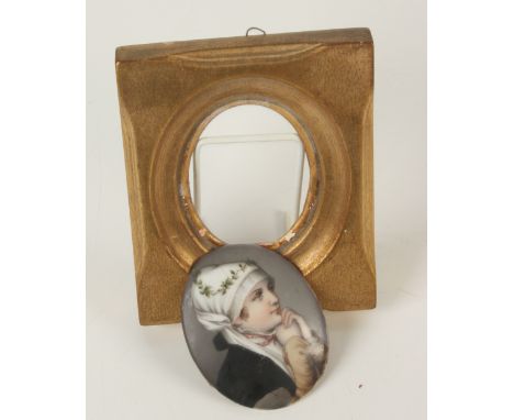 An oval porcelain plaque, decorated with a female figure wearing a white head scarf, in a gilt wood frame, size of plaque 8.4