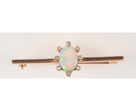 A gold fire brooch with an oval opal surrounded by eight diamonds.