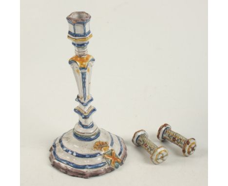 An 18th century faience candlestick and a pair of faience holly chrome knife rests.