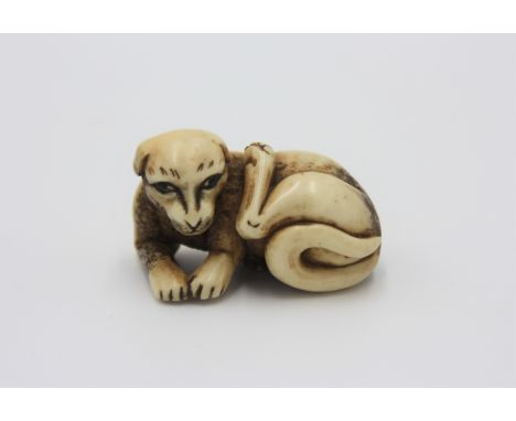 A bone netsuke carved as a dog, early 20th century, height 2cm, width 4.2cm.