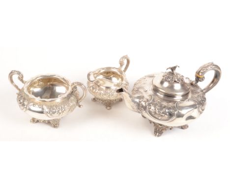 A ornate three piece silver service with floral and acanthus repousse decoration comprising a teapot with flower finial, a mi