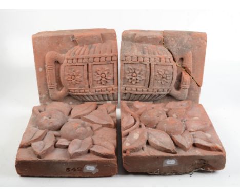 Four terracotta architectural tiles, one pair decorated with fruit and leaves, the other an urn, impressed 542, each height 3