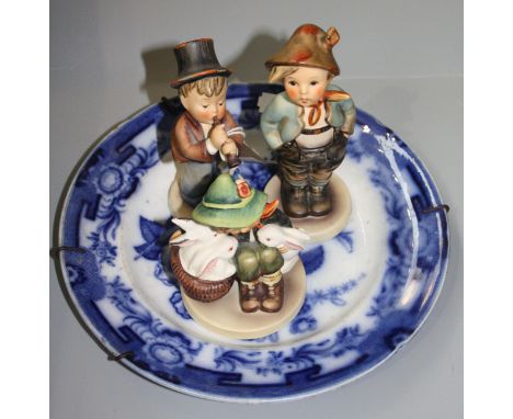 Three Hummel figures and a blue and white plate.