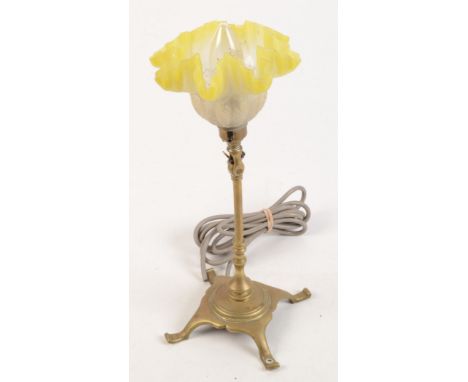 An Arts and Crafts brass adjustable table lamp, with a yellow flashed glass shade, extended height 36cm, width of base 14cm. 