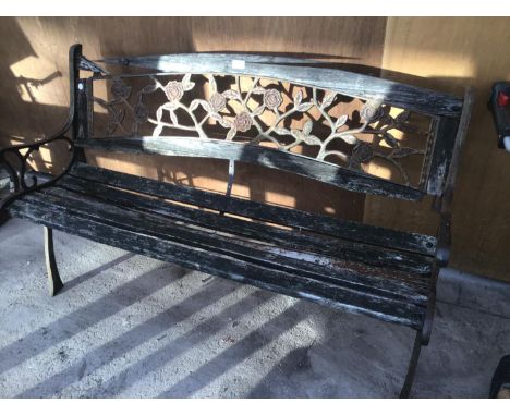 A WOODEN BENCH WITH CAST IRON ENDS AND A CAST IRON ROSE DESIGN BACK 