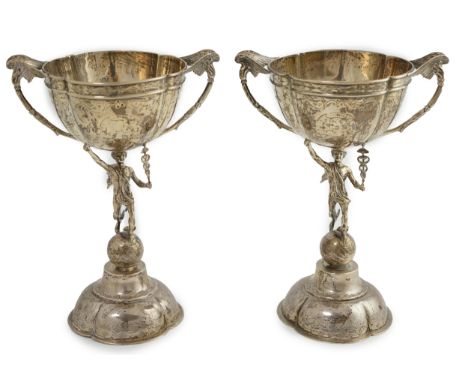 A pair of Victorian silver two handled pedestal cups, each figural stem modelled as Hermes upon a globe, by Edward Charles Br