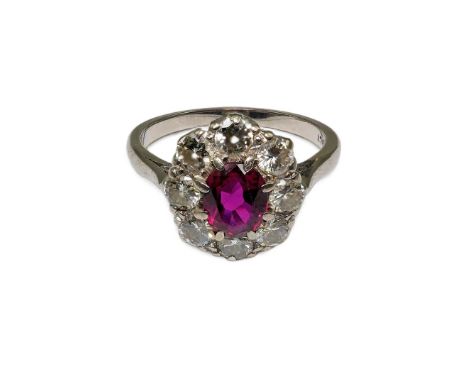 An 18ct white gold, ruby and diamond set oval cluster ring, size O, gross weight 4.1 grams.  One of the diamonds is chipped o