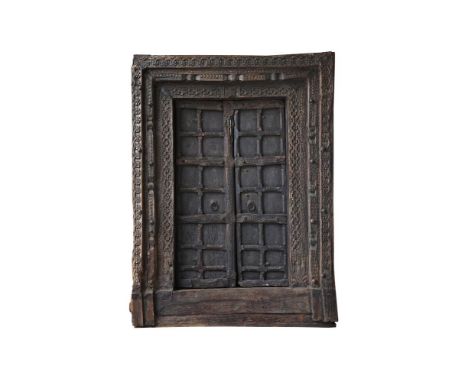 An impressive carved wood doorway, India, probably Rajasthan, 18th or 19th century, the double doors with panelling and iron 
