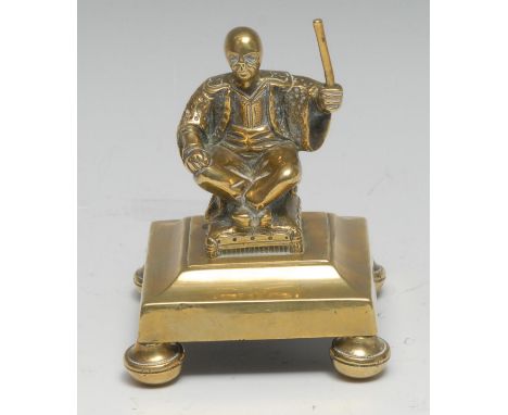 A post-Regency gilt brass desk weight, cast in the Chinioserie taste with a Chinese figure, seated, raising a baton, square b