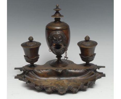 A 19th century Grand Tour brown patinated bronze ink stand, the central lamp cast with an Egyptian mask, flanked by a pair of