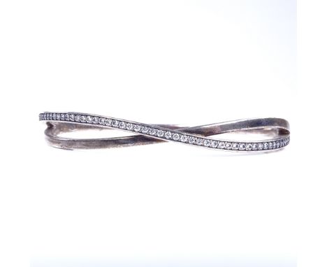 PANDORA - a modern sterling silver and CZ crossover hinged bangle, band width 6.4mm, internal dimensions 60mm x 50cmm, 16.9gV