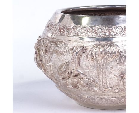 An early 20th century large Burmese silver rice bowl, high relief body depicting hunting lion scenes, elephant maker's mark w