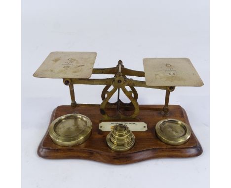 A set of brass postal scales and weights, with plaque displaying inland letter rates, length 24cm 