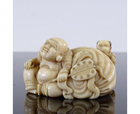 A Japanese ivory netsuke in the form of a man and child resting on a sack, Meiji Period, length 4cm 