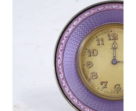 An early 20th century purple enamel and unmarked white metal-framed 8-day circular mantel clock, champagne dial with Arabic n