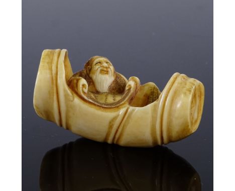 A Japanese carved stained ivory netsuke, depicting a scholar seated in a barrel, Meiji Period, length 5.5cm 