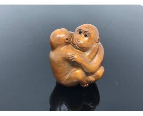 A carved hardwood netsuke  - Two monkeys embracing