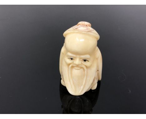 A carved bone netsuke  - bearded man wearing a cap