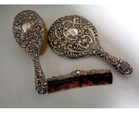 A three piece silver backed and edged dressing table brush, hand mirror and comb set 