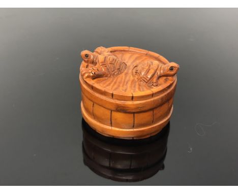 A carved hardwood netsuke  - turtles in a barrel 