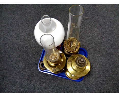 Four 20th century oil lamp bases, three with chimneys, one with shade 