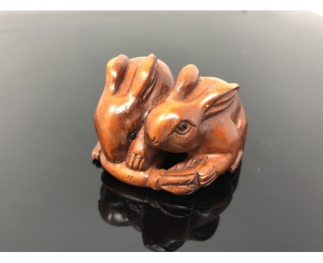 A carved hardwood netsuke  - Two rabbits