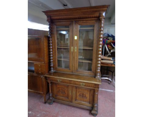 A 19th century oak double door bookcase with bobbin column supports, fitted cupboards beneath 