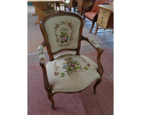 A carved beech framed French salon armchair upholstered in a tapestry fabric  