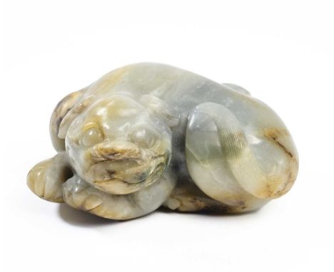 A CHINESE CELADON JADE LION the recumbent feline with head resting on its front paws and tail swished over its rear haunches,