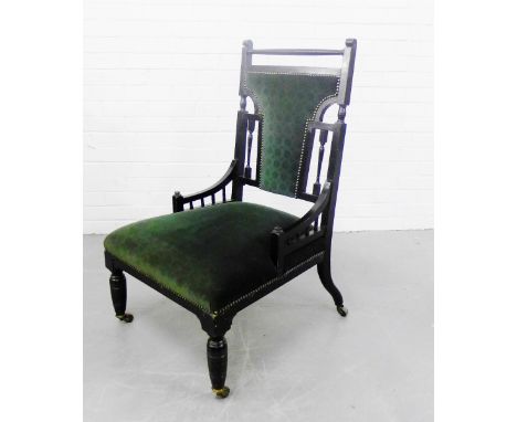 An ebonised aesthetic style chair with padded back and seats on turned supports with brass caps and ceramic castors, 96 x 60c