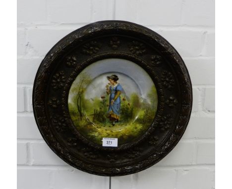 An enamel plate painted with a female figure to centre all contained within a bronzed metal surround, 40cm diameter 
