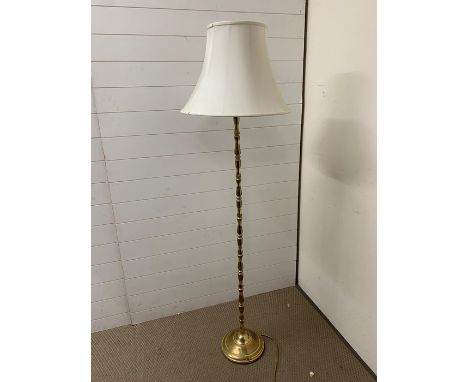 A floor standing brass lamp with white shade 