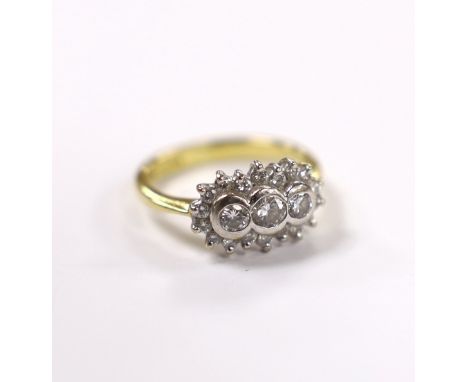 A modern 18ct gold and collet set three stone diamond ring, with diamond chip set border, size J/K, gross weight 4.6 grams.**