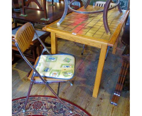 A mid-20th century pine kitchen table with tile inset, together with two folding chairs.