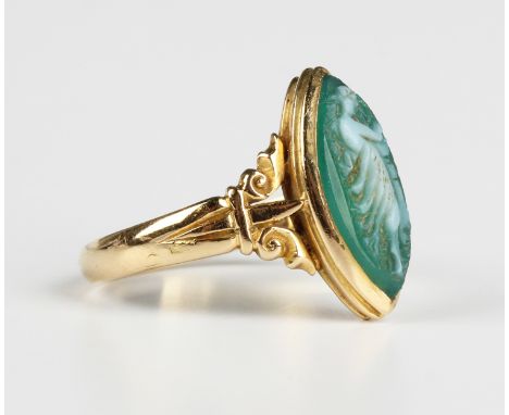 An Edwardian 18ct gold ring, mounted with a marquise shaped dyed green agate cameo, carved as a classical lady, between decor