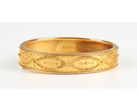 A late Victorian 15ct gold oval hinged bangle, the front applied with bead and wirework decoration in the classical taste, Ch